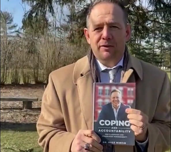Dr. Buzz Mingin holding his book Coping and Accountability for Classroom and Schoolwide Management